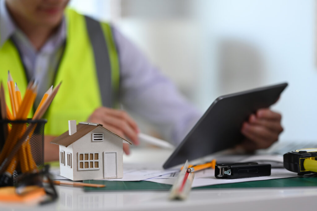 Architect workspace with house model and blueprints representing home insuran